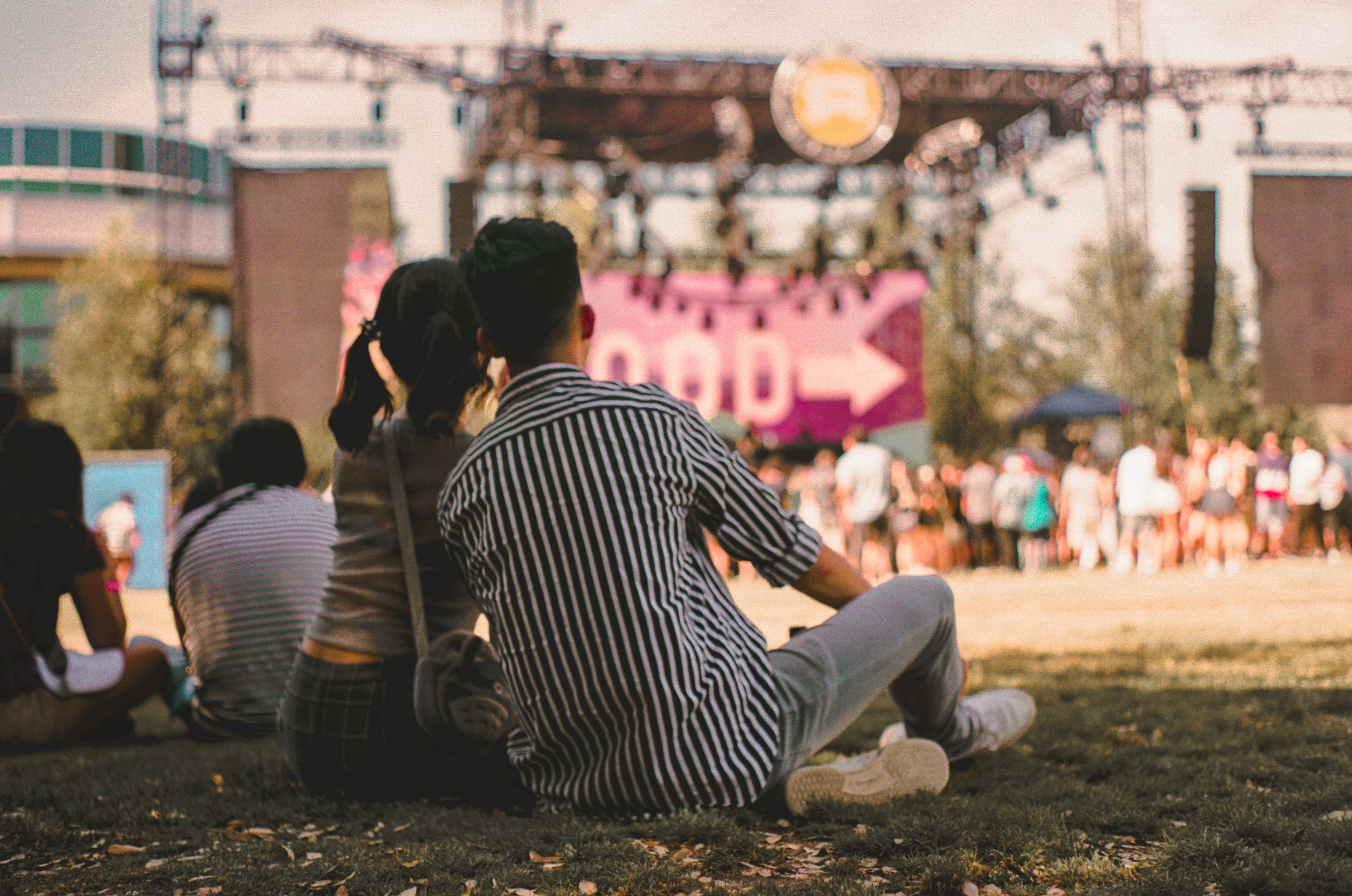 Couple relaxing on grass at a sunny outdoor music festival, highlighting the importance of comfortable rest areas.